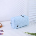 Vue détaillée de la trousse à maquillage matelassée bleu clair avec broderie nœud noir et zip - Trousse de Maquillage Bleue