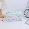 Quilted floral pencil case with green zipper shown in a cozy desk setting - Green