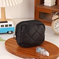 Détail d'une pochette matelassée noire avec fermeture éclair sur un plateau en bois - Noir