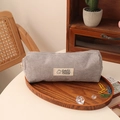 Detailed shot of grey corduroy pencil case with bear patch in a cozy wooden tray - Gray