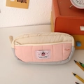 Detail of a quilted tricolor pencil case with a cream pudding patch on a desk - Pink