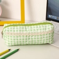 Close-up of green plaid pencil case with diamond quilting and lace detail on a desk - Green