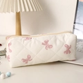 Détail de la trousse matelassée blanche avec imprimé nœuds roses sur un bureau blanc - Nœud Rose