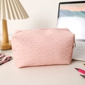 Detail der rosa gewebten PU-Leder Kosmetiktasche mit Metallreißverschluss auf dem Tisch - Orangerosa
