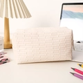 Detail of cream woven makeup bag on a desk with aesthetic home office decor - Beige