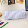 Detailed view of seersucker pencil case with blue stripes and green zipper on a desk - Lake Blue Stripe