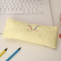 Detailed close-up of yellow quilted pencil case with colorful bow embroidery - Yellow