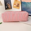 Detail of red striped seersucker pencil case with vibrant red zipper on a desk - Red Stripes