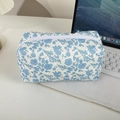 Detailaufnahme einer gesteppten Baumwolltasche mit Blumenmuster und weißem Reißverschluss - Weiß mit blauen Blumen