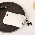 Close-up of white quilted cosmetic bag with black bow embroidery and pearl zipper detail - Off White