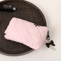 Pink quilted makeup bag with black bow charm and pearl detail on a woven tray - Pink