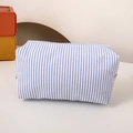 Detailed view of blue and white striped fabric pouch with secure zipper closure - Blue