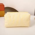 Detailed close-up of yellow and white striped canvas pencil case with a zipper closure - Yellow