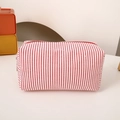 Close-up of red and white striped cotton pencil case with metal zipper on a desk - Red