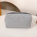 Close-up of minimalist black and white striped canvas pencil case with metal zipper detail - Black