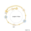 Détail d'un bracelet fleuri avec breloques bleues et blanches sur chaîne dorée - Style Fleur Bleue en Nacre (BR29870MG)