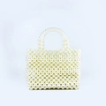Close-up detail of handcrafted rectangle pearl beaded handbag with woven satin finish - White
