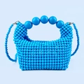 Close-up of blue beaded handbag showing large bead handles and woven pearl texture - Blue