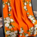 Gros plan sur l'élégant imprimé camélia orange sur la texture lisse du foulard en satin - 180*90CM / Camélia Orange