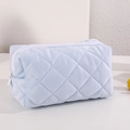Detailansicht der hellblauen gesteppten Stofftextur und des weißen Reißverschlusses der Tasche - Blau