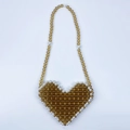 Detail of amber beaded heart bag with white pearl border trim and stylish woven strap - Brown