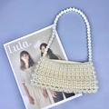 Detailed top view of handmade beaded pearl shoulder bag on a magazine background - White