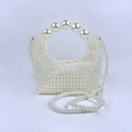 Detailopname van handgeweven parel-avondtas met groot parelhandvat en elegante riem - Broken Wit