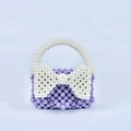 Macro detail of purple handmade beaded handbag with white pearl bow decoration - Violet