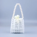 Elegant white beaded mini handbag with grid pattern and pearl handle on light blue backdrop - Clear
