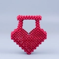Gros plan sur le sac à main perlé rouge en forme de cœur avec une texture brillante - Rose rouge