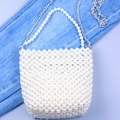 Detail einer handgefertigten Perlen-Beuteltasche mit silberner Kette auf Denim-Hintergrund - Weiß+Silber