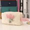 Close-up of cream corduroy makeup bag featuring pink tulip embroidery and quilted texture - Beige
