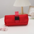 Detail of red cylindrical pencil case with buckle closure on a desktop setting - Red