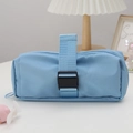 Close-up of light blue nylon pencil case with buckle strap in a cozy desk setting - Blue