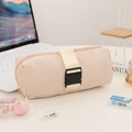 Detailed view of beige canvas pencil case with a decorative buckle strap on a clean desk - Beige