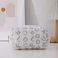 Detalle de bolsa de lona blanca acolchada con letras grises y cremallera en escena minimalista - Morado