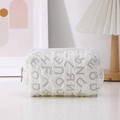 Close-up of white quilted puffer canvas bag with letter texture and zipper closure - Green