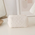 Close-up of a white plush pencil case featuring quilted texture and a gold metal zipper - White
