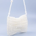 Makroaufnahme der handgefertigten weißen Perlen-Handtasche mit Schleifen-Design und Kette - Weiß