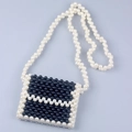 Detalle de minibolso artesanal de cuentas negras con borde de perlas blancas - Blanco + Negro