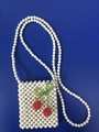 Close-up of handmade acrylic bead bag featuring red cherry decor on a white woven texture - White+Red+Green