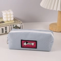 Detailed view of light blue fabric pencil case with dog tag on minimalist white desk - Pink Large Label Puppy Pencil Case