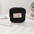 Dettaglio mini trousse nera trapuntata con etichetta motivazionale in stile pulito - Nero
