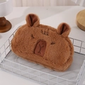 Dettaglio dell'astuccio in peluche marrone a forma di capibara con ricami in un cesto - Astuccio Capibara (Occhi Socchiusi)