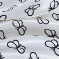 Macro shot of silk satin fabric showing black butterfly print and glossy texture - White Butterfly