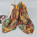 Silk satin square scarf with colorful paisley print draped over a beige leather handbag - Orange Yellow Paisley