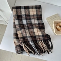 Detail of soft plaid scarf in black and beige with dense fringe on a white desk - Black