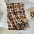 Close-up of a plaid scarf with soft tassels in brown and beige on a white desk - Coffee Camel