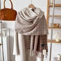 Dettaglio di sciarpa in maglia a quadri marrone e beige con nappe su cappotto beige - Cachi