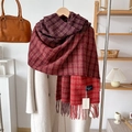 Dettaglio di sciarpa a quadri rossi con frange abbinata a un cappotto bianco invernale - Rosso
